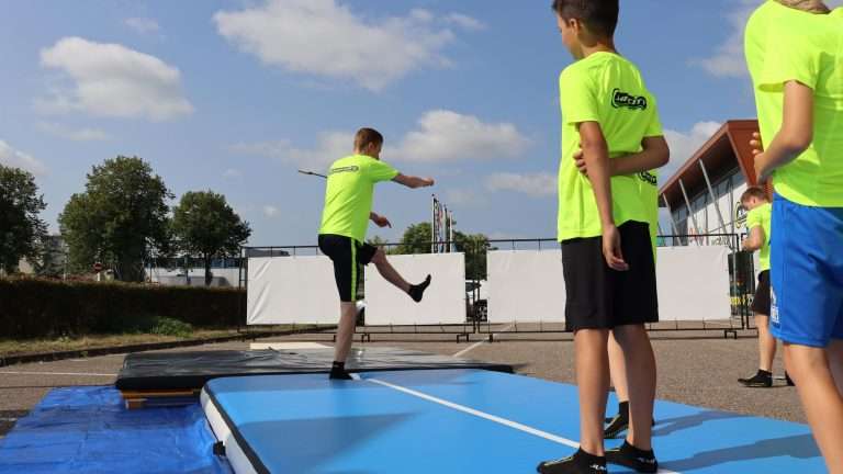 Atleet voert een truc uit op een outdoor airtrack