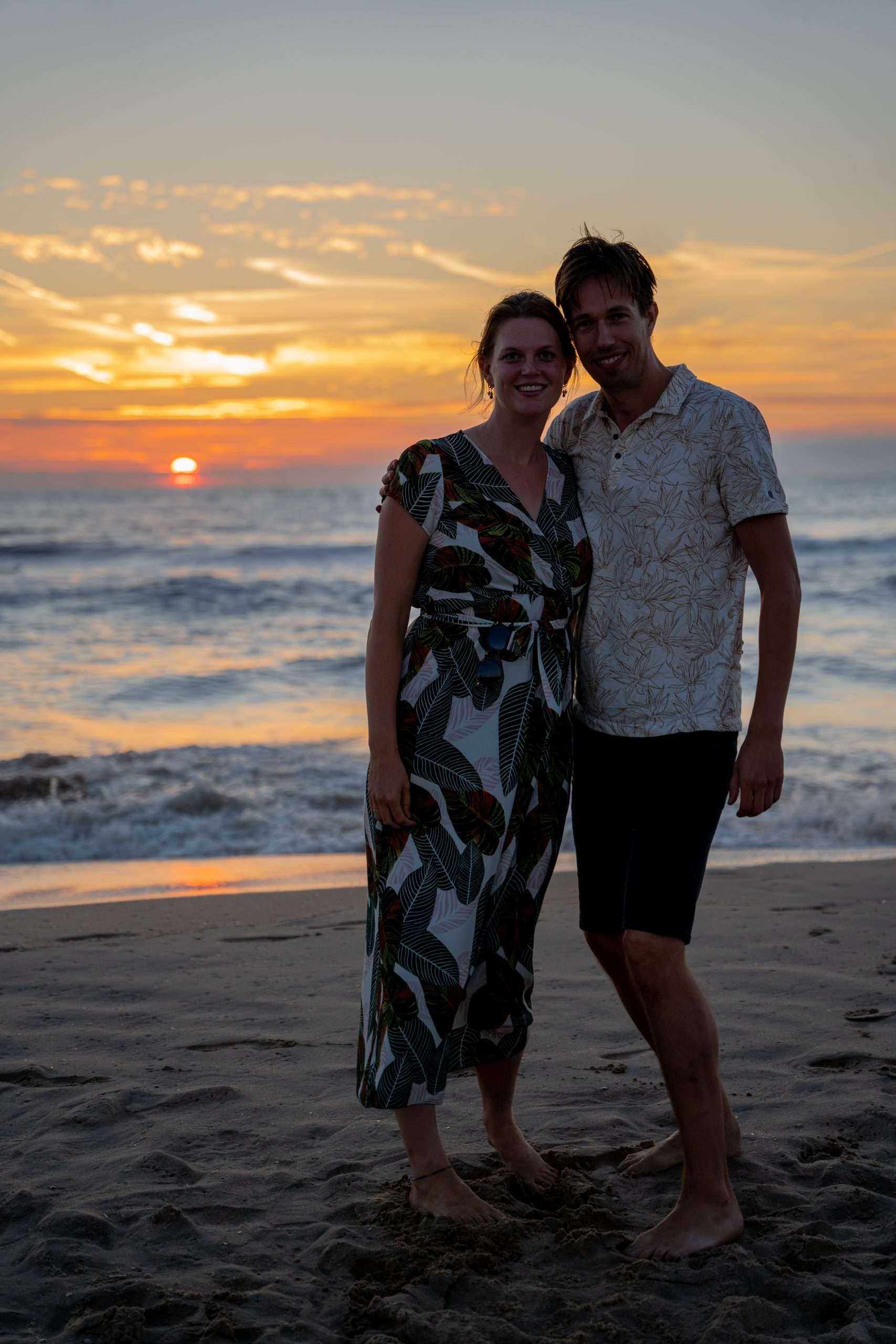 Koppel poseert op het strand bij zonsondergang