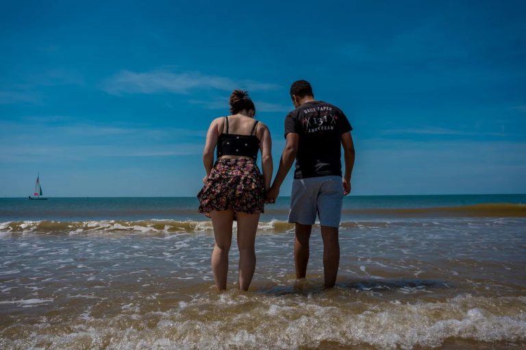 Koppel loopt hand in hand het ondiepe zeewater in